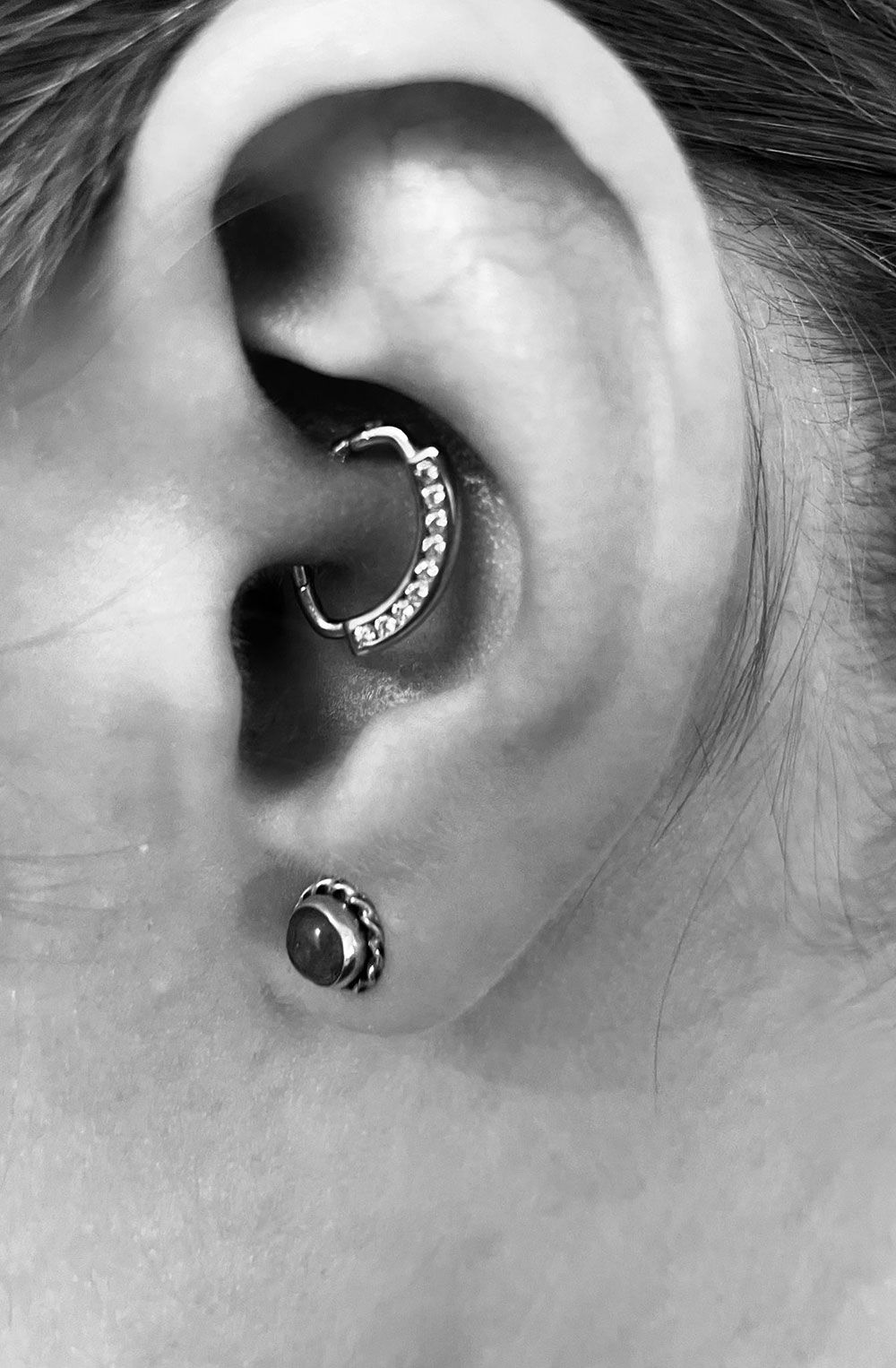 Eine Nahaufnahme des Ohrs einer Frau mit Ohrringen und einem Piercing.