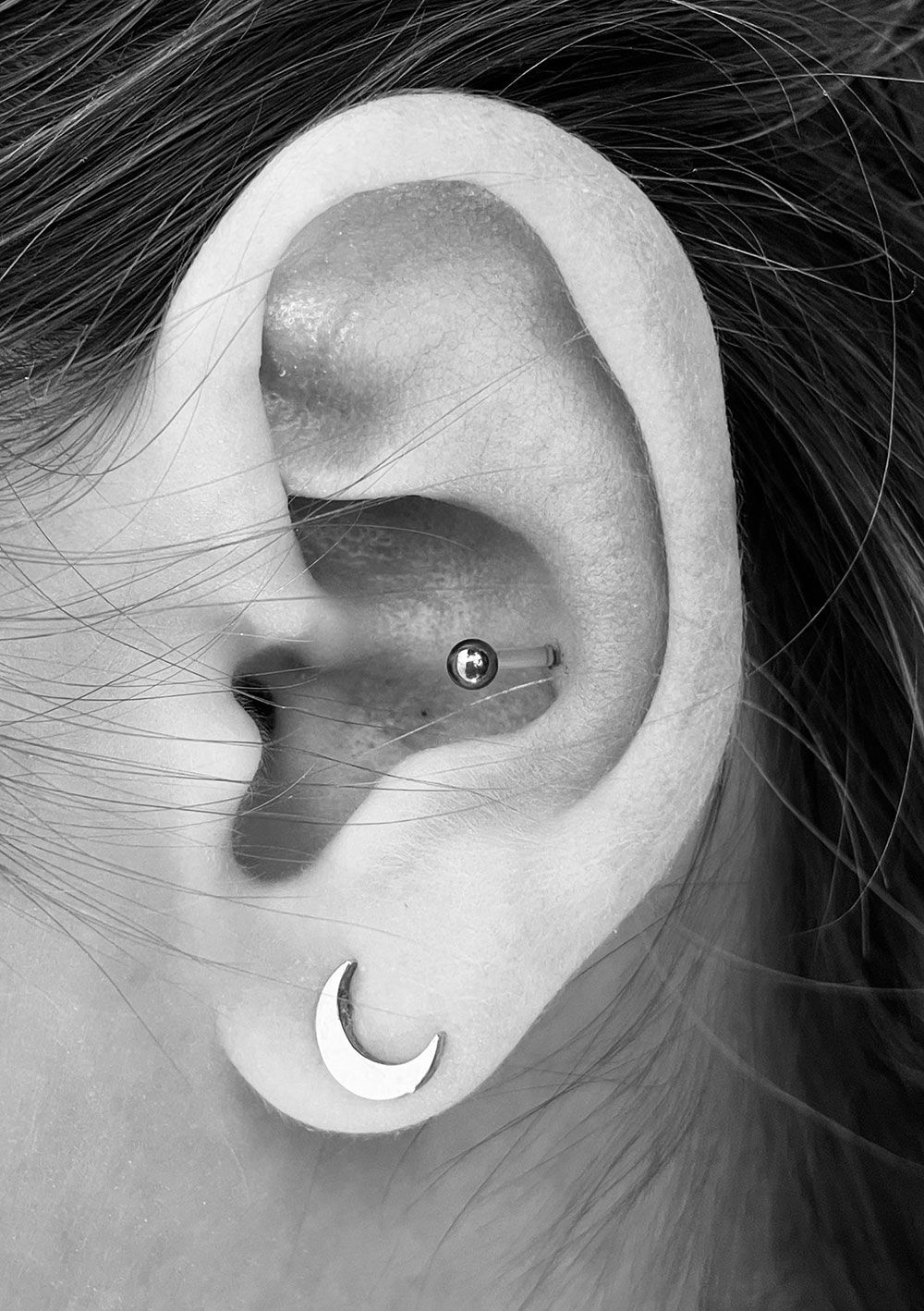 Eine Nahaufnahme des Ohrs einer Frau mit Piercings und Ohrringen.