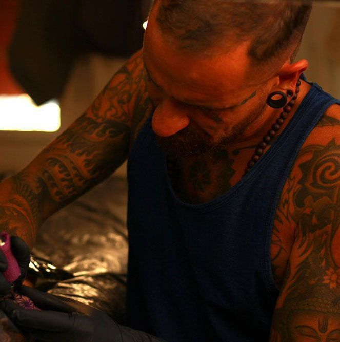 Ein Mann mit vielen Tattoos auf den Armen lässt sich tätowieren