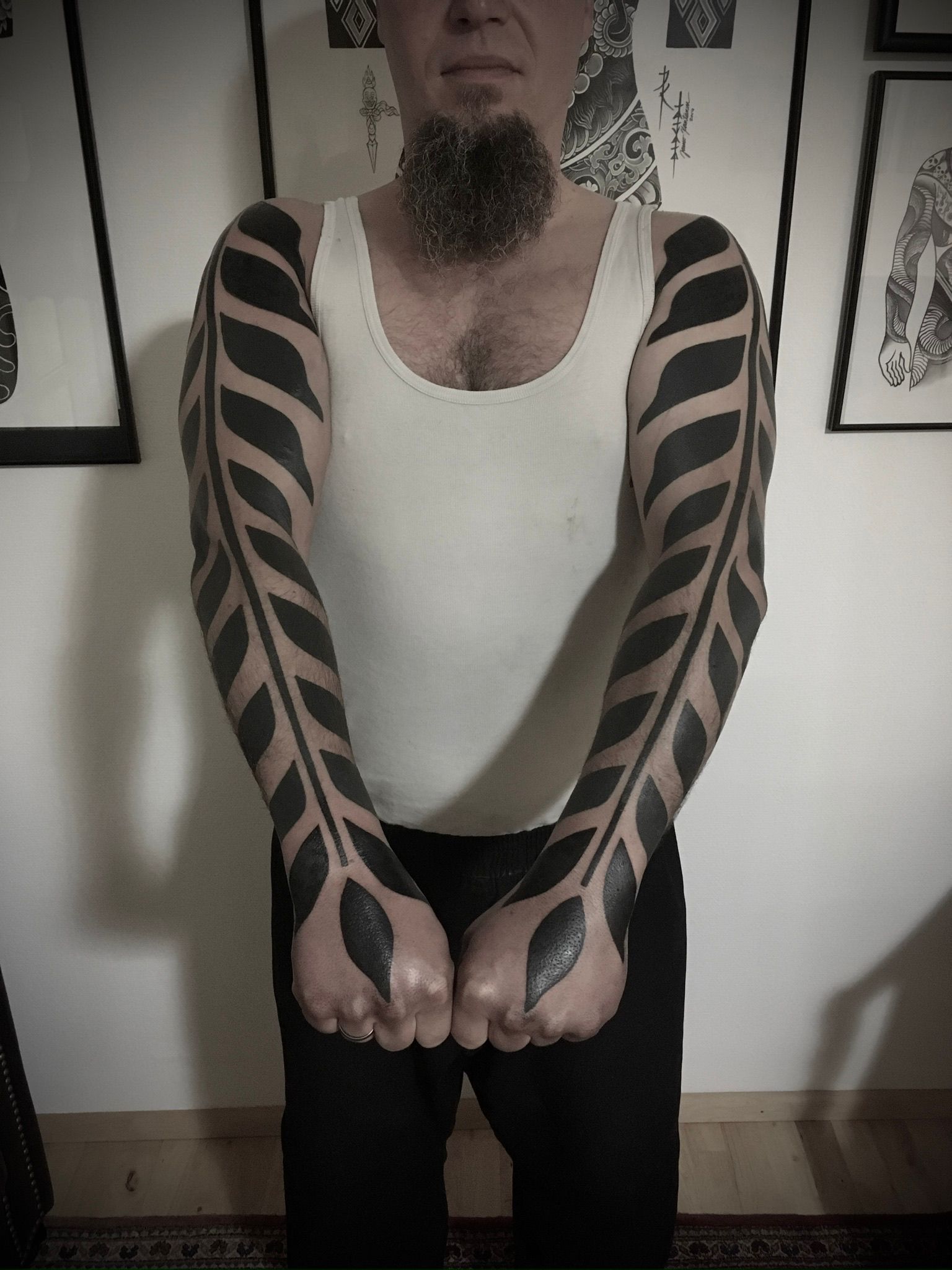 Ein Mann mit Bart hat schwarze Tattoos auf den Armen
