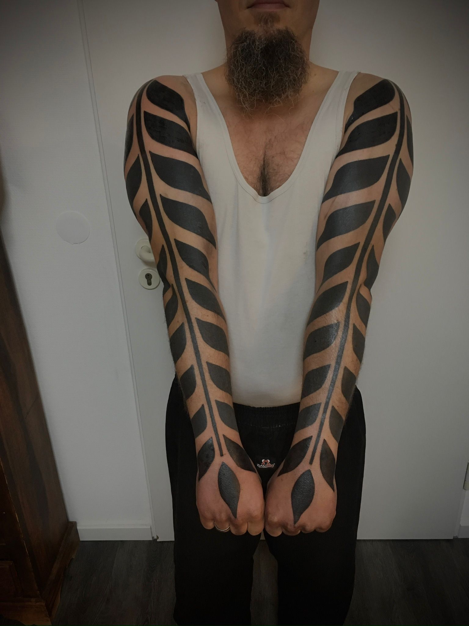 Ein Mann mit Bart und schwarzen Tattoos auf den Armen