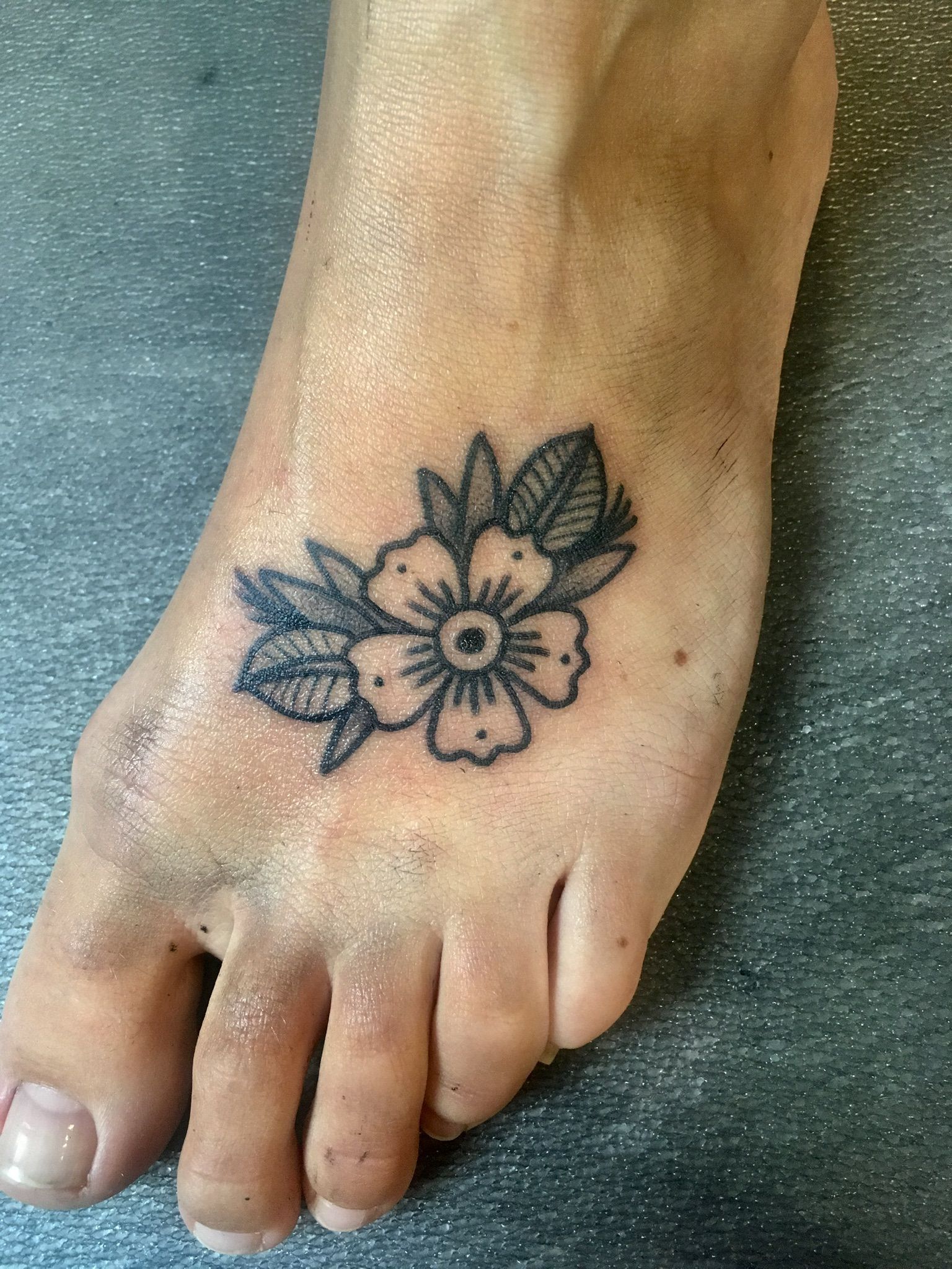 Eine Person hat eine Blumentätowierung auf ihrem Fuß.