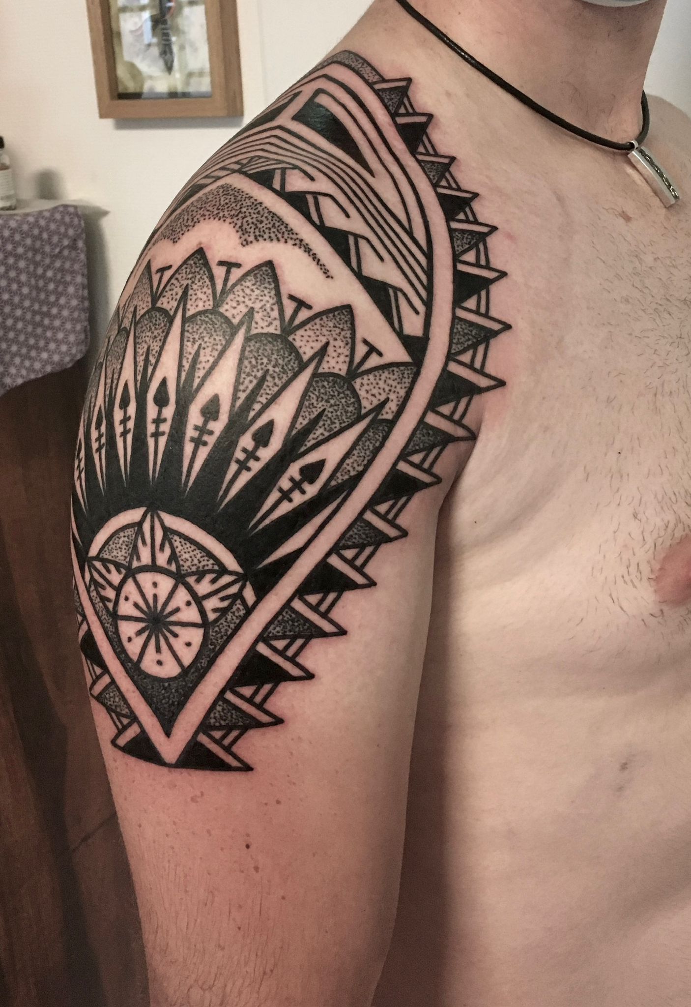 Ein Mann hat ein Tattoo auf seiner Schulter, das wie ein Fächer aussieht