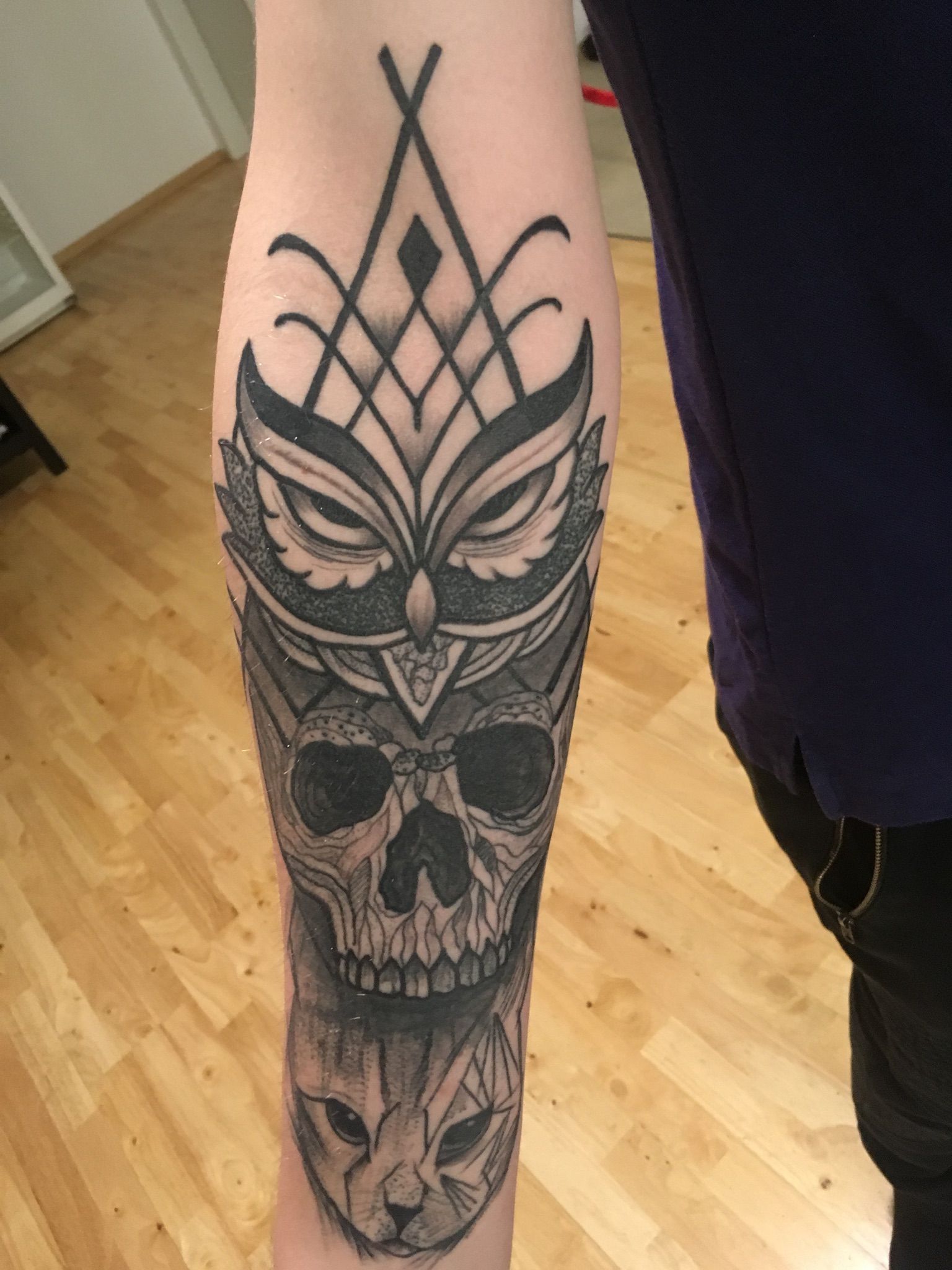 Eine Person hat eine Tätowierung einer Eule und eines Totenkopfes auf dem Arm.