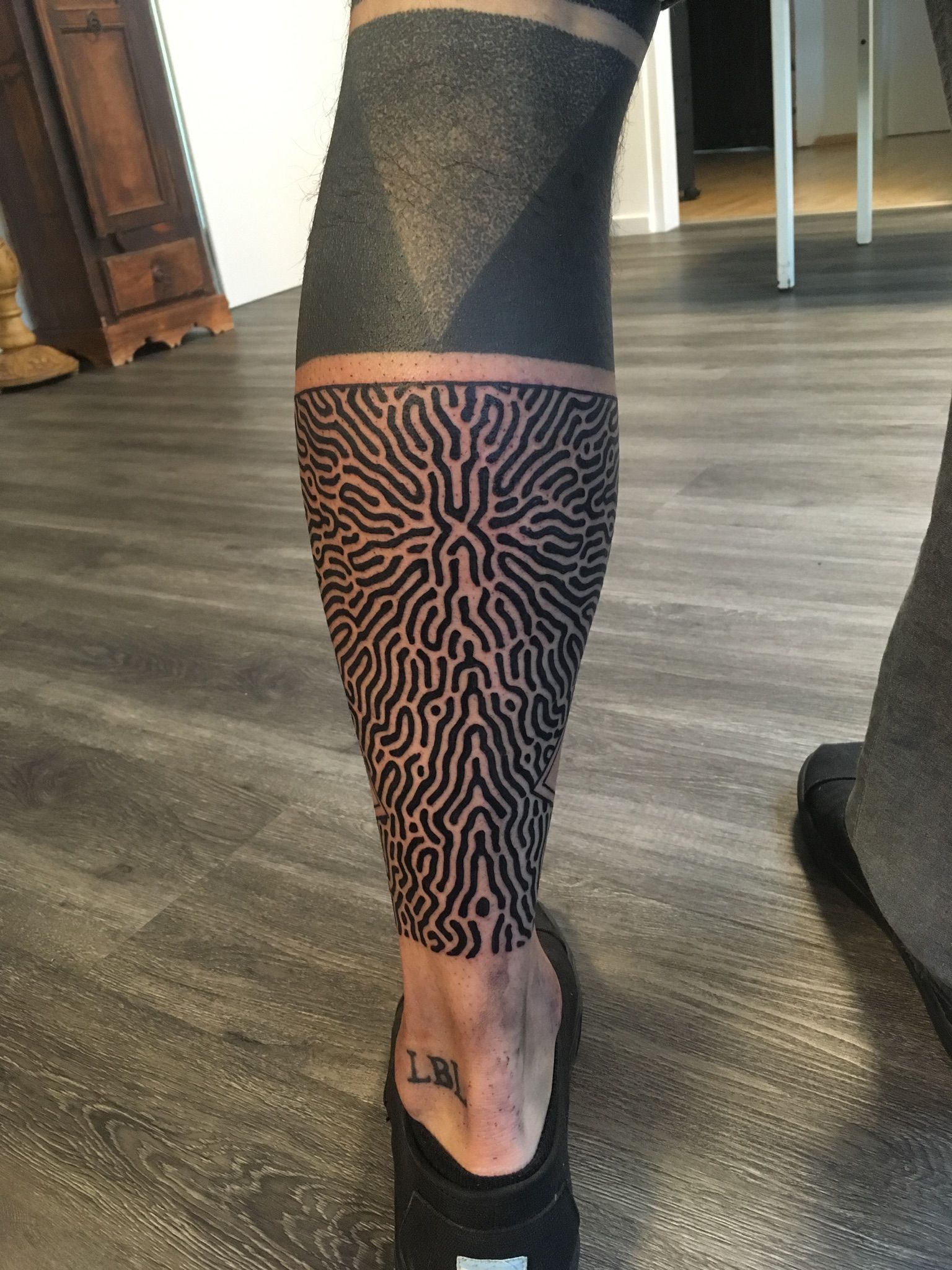 Eine Person mit einer schwarz-weißen Tätowierung auf dem Bein.