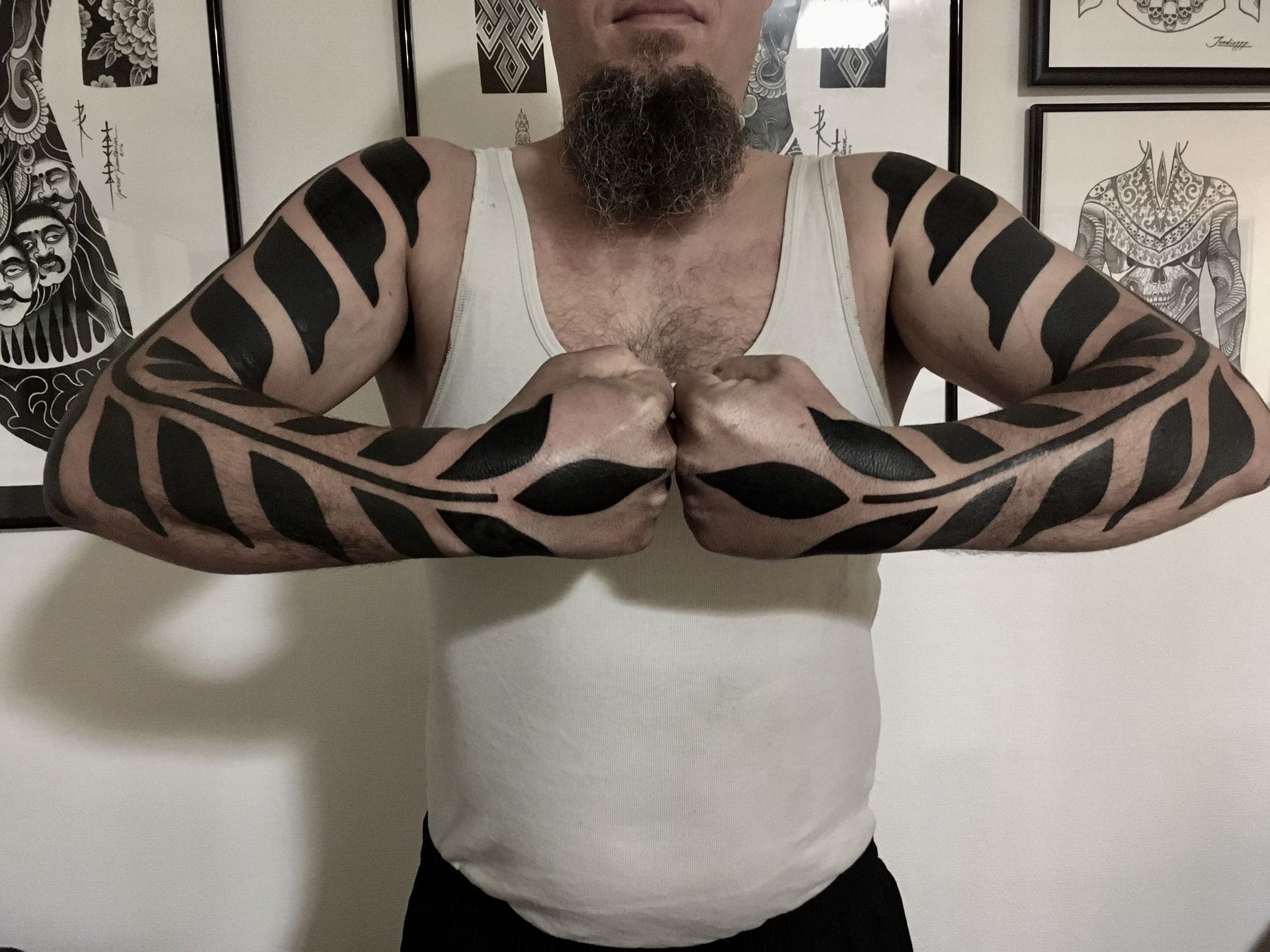 Ein Mann mit Bart hat schwarze Tattoos auf den Armen