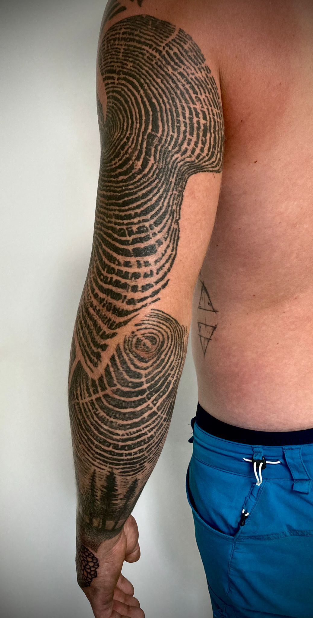 Ein Mann mit einer Tätowierung auf dem Arm trägt blaue Shorts.