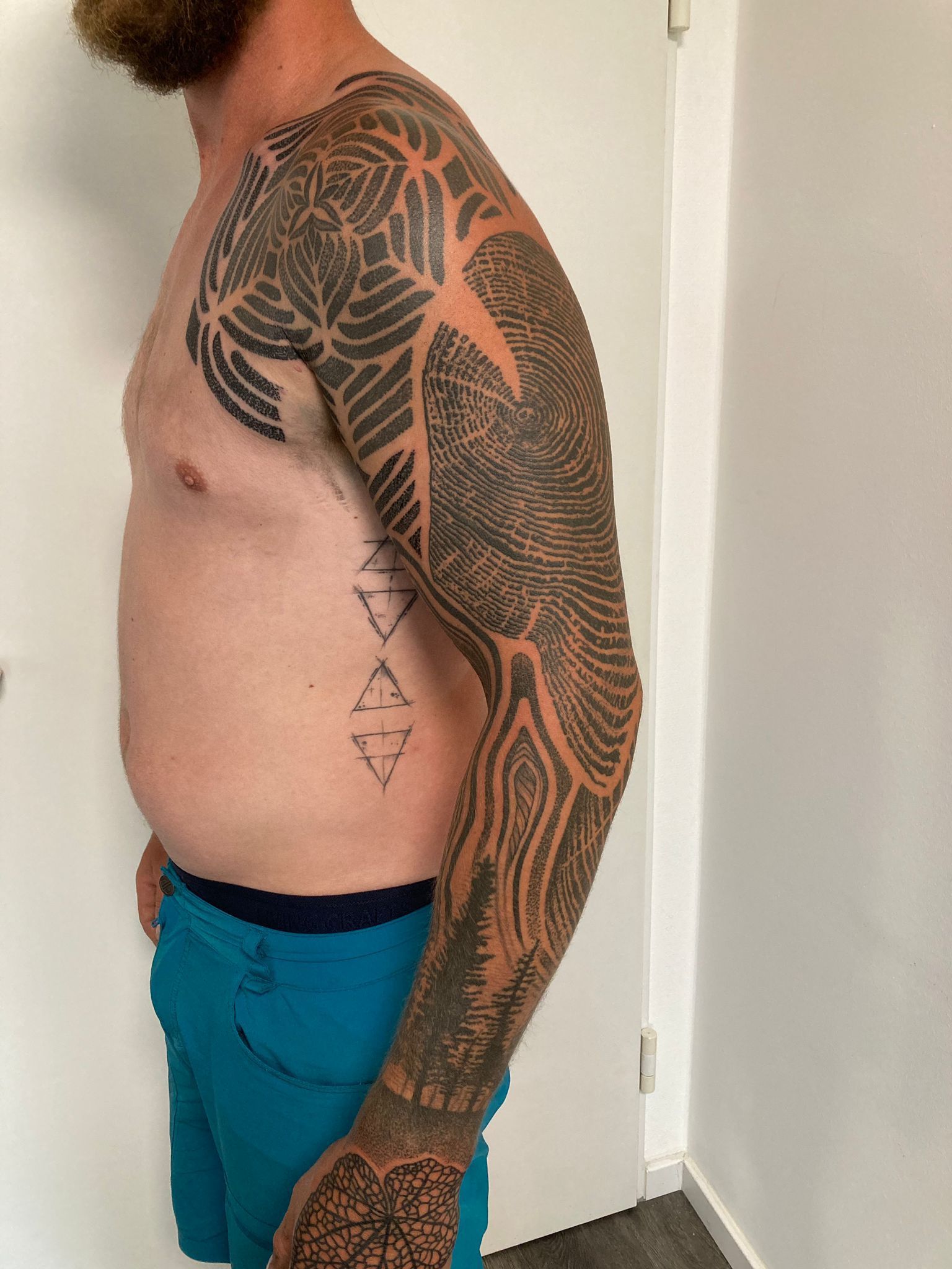 Ein Mann ohne Hemd mit einer Tätowierung auf dem ganzen Arm.