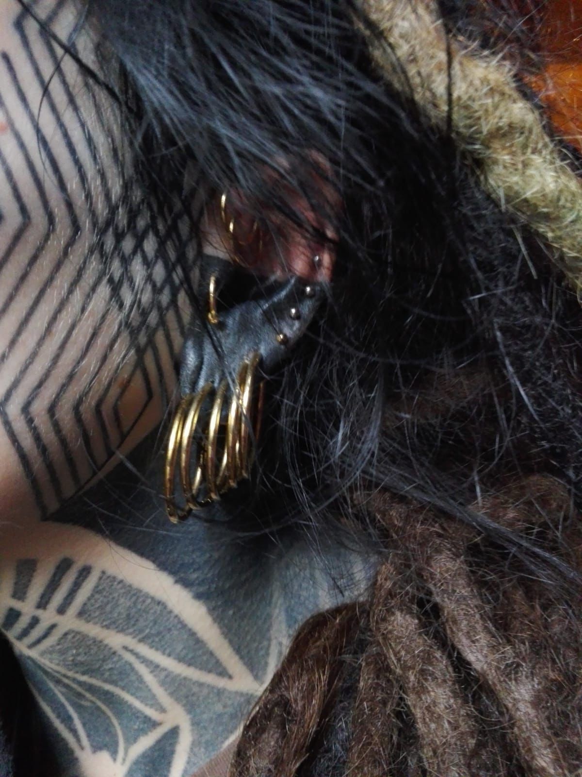 Eine Nahaufnahme einer Person mit einer Tätowierung im Gesicht und am Ohr.