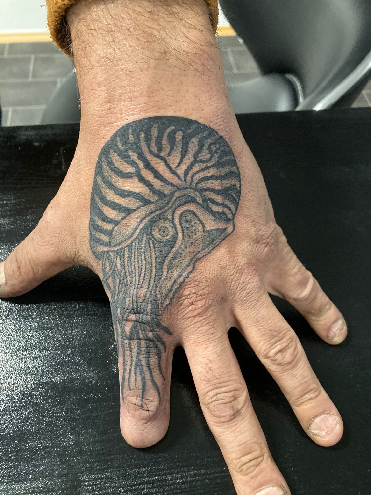 Eine Nahaufnahme der Hand einer Person mit der Tätowierung eines Oktopus darauf.