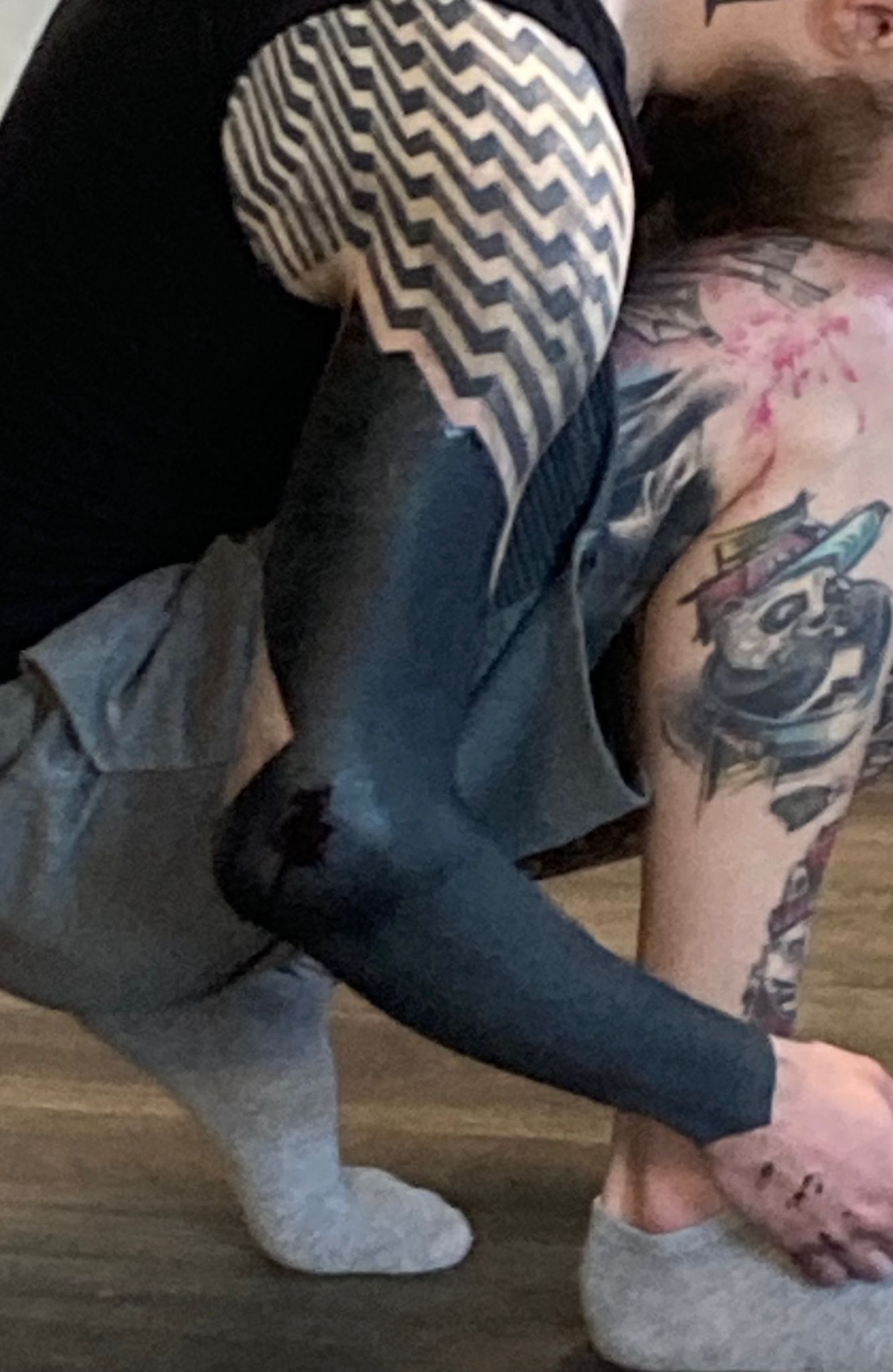 Ein Mann mit einer schwarzen Tätowierung auf dem Arm kniet nieder.