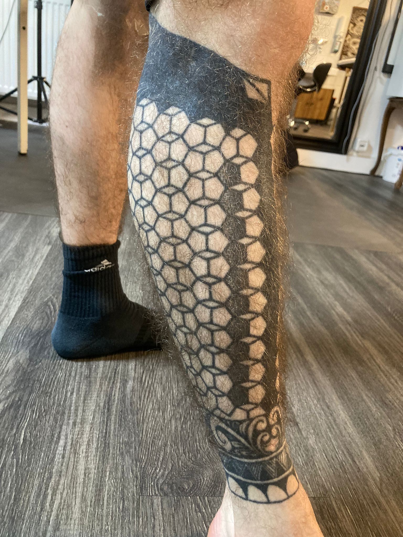 Ein Mann mit einer schwarz-weißen Tätowierung auf seinem Bein.