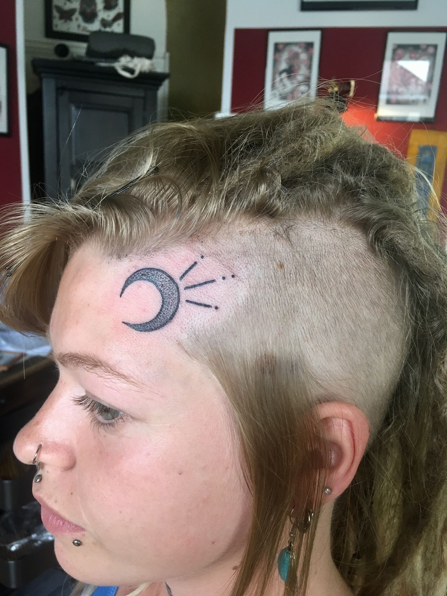 Eine Frau hat eine Mondsichel-Tätowierung auf der Stirn.