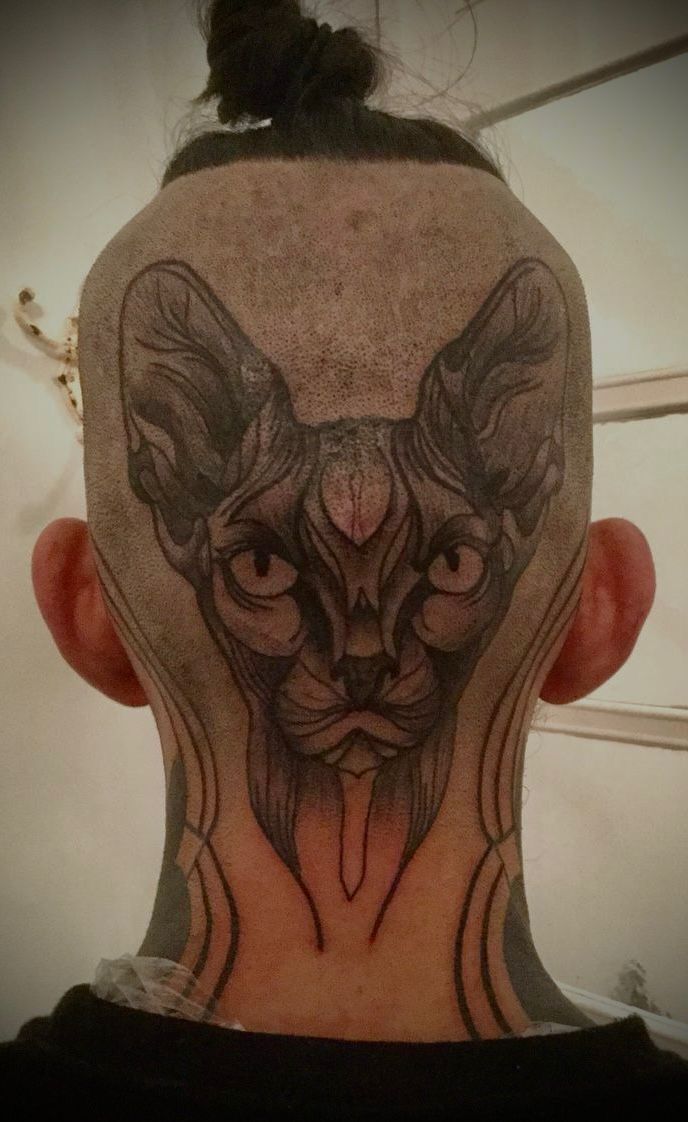 Ein Mann hat eine Katzentätowierung auf dem Kopf.