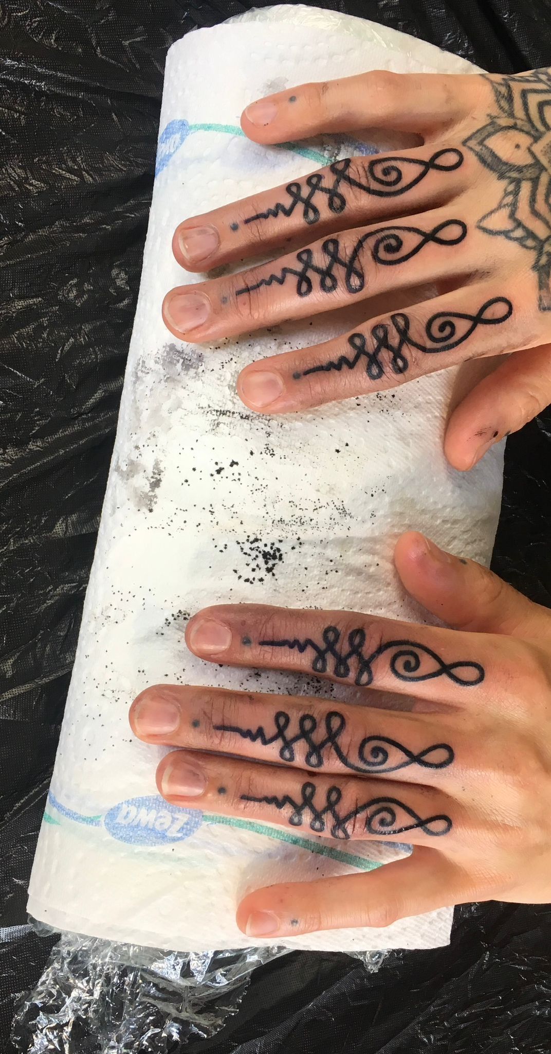 Eine Person mit einer Tätowierung auf den Fingern hält eine Rolle Papierhandtücher.