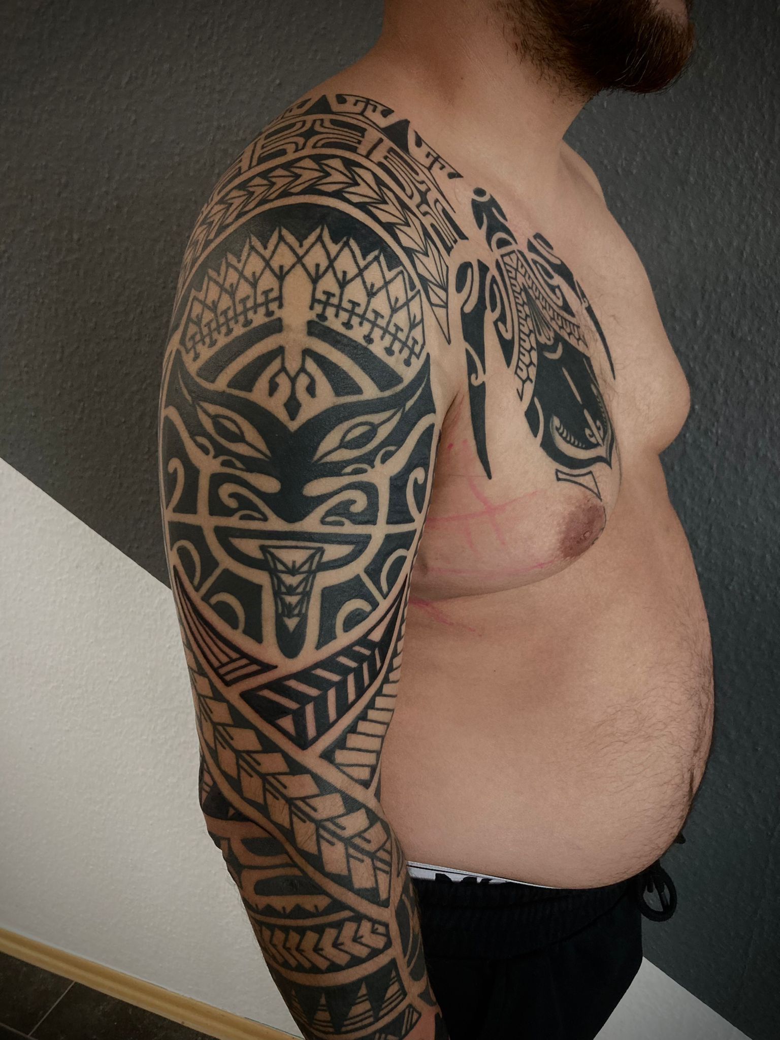 Ein Mann mit einer Tätowierung auf Arm und Brust