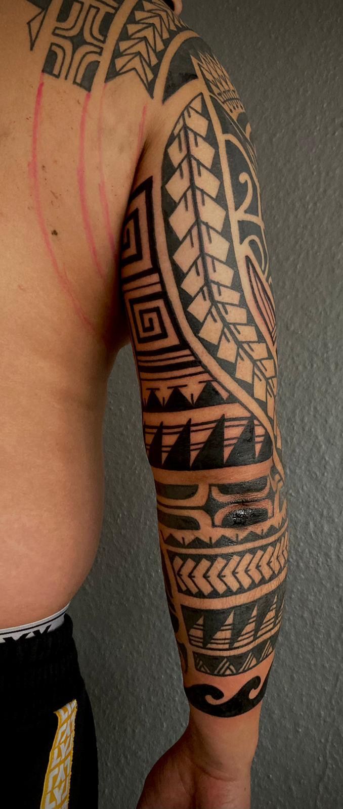 Ein Mann mit einem Stammes-Tattoo auf Arm und Schulter.