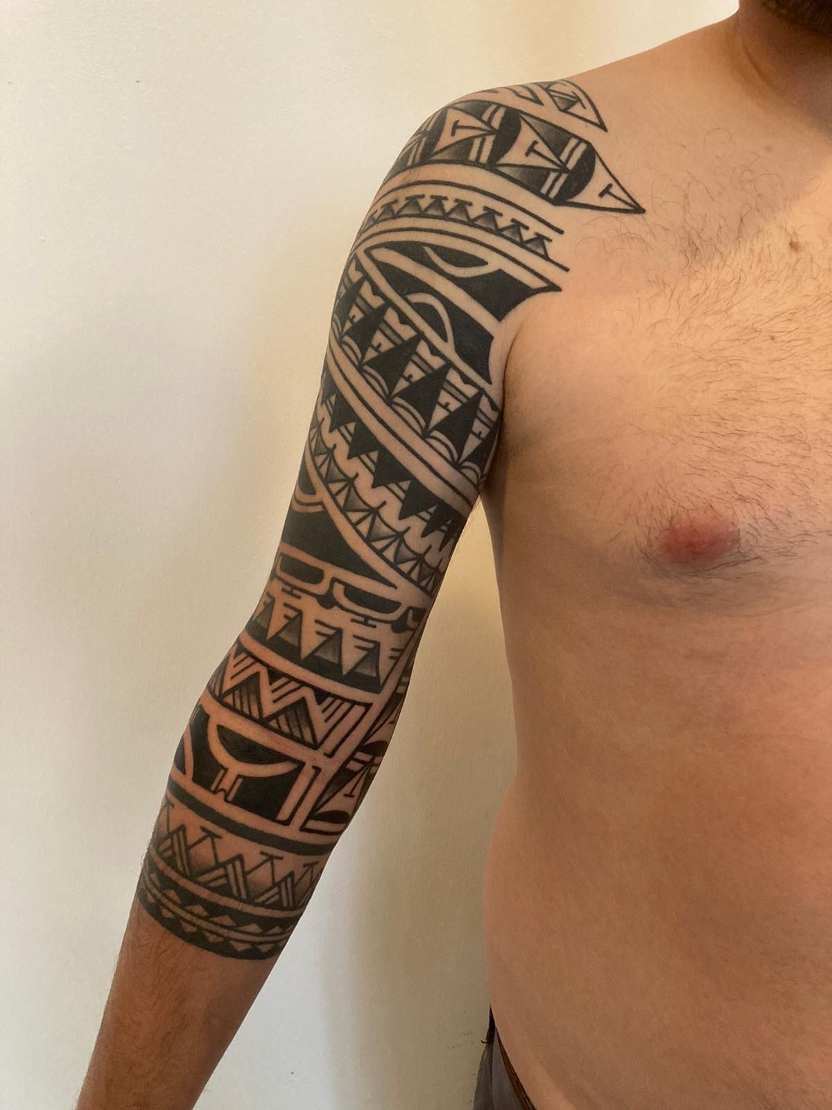 Ein Mann ohne Hemd hat ein Tribal Tattoo auf seinem Arm