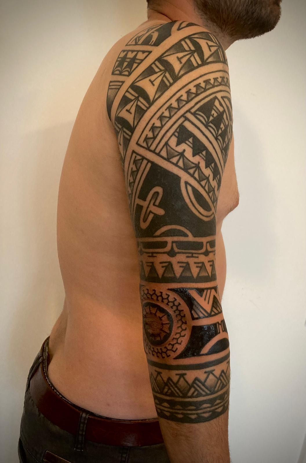 Ein Mann ohne Hemd hat ein Stammestattoo auf seinem Arm.