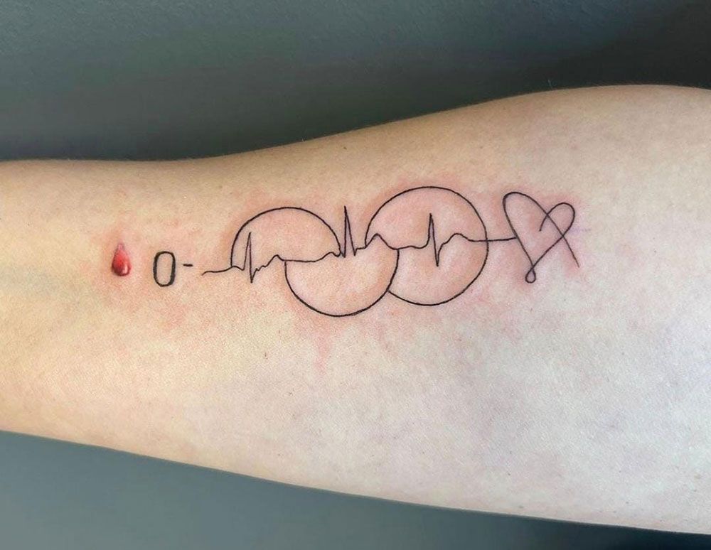 Eine Person hat eine Tätowierung mit einem Herzschlag und einem Herzen auf dem Arm.