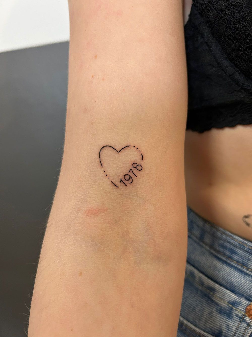 Eine Frau hat ein kleines Herztattoo auf ihrem Arm.