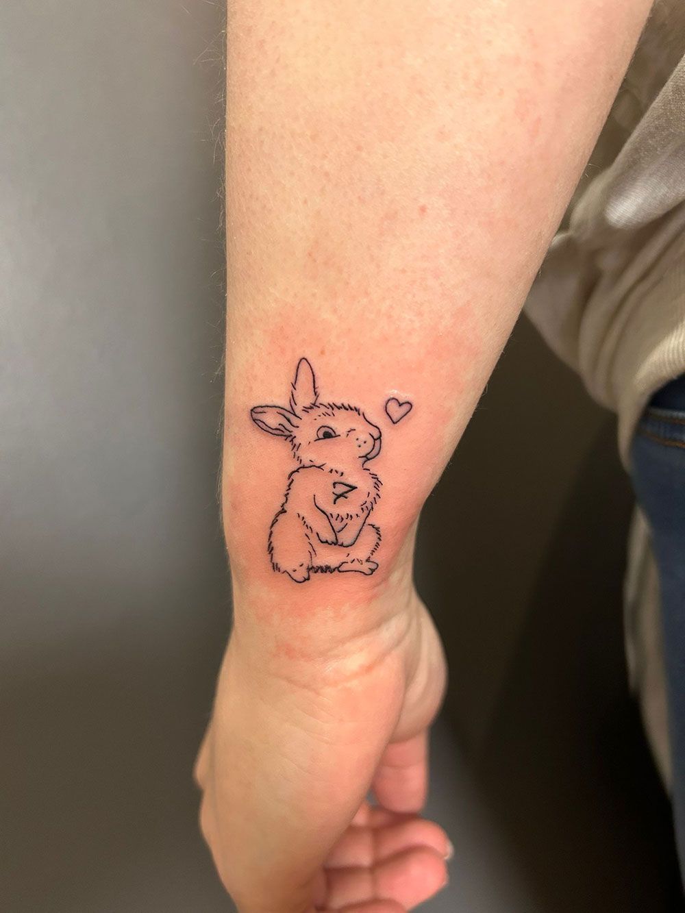 Eine Person hat eine Kaninchentätowierung auf ihrem Handgelenk.