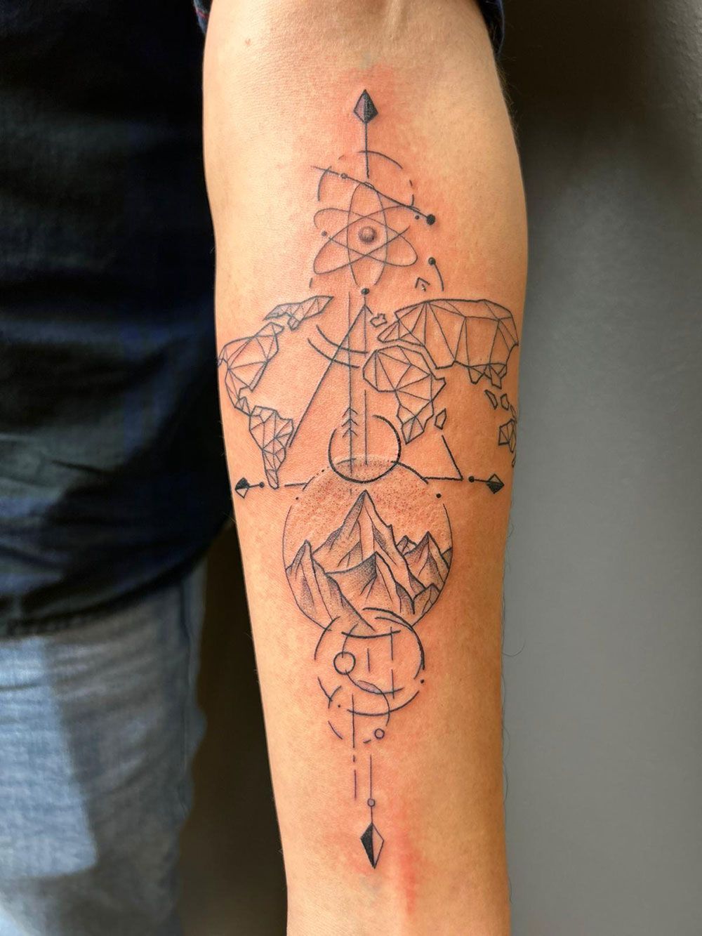 Eine Person hat eine Tätowierung auf dem Unterarm, die wie eine Weltkarte aussieht.