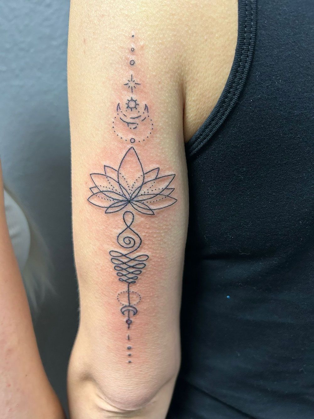 Eine Frau hat eine Tätowierung einer Lotusblume auf ihrem Arm