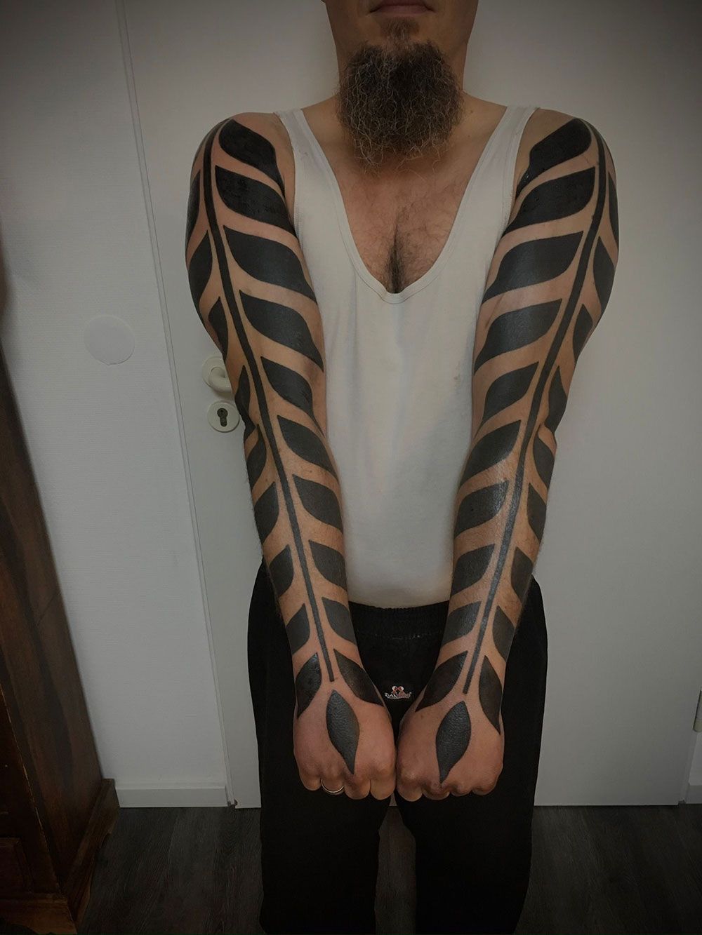 Ein Mann mit Bart und schwarzen Tattoos auf den Armen