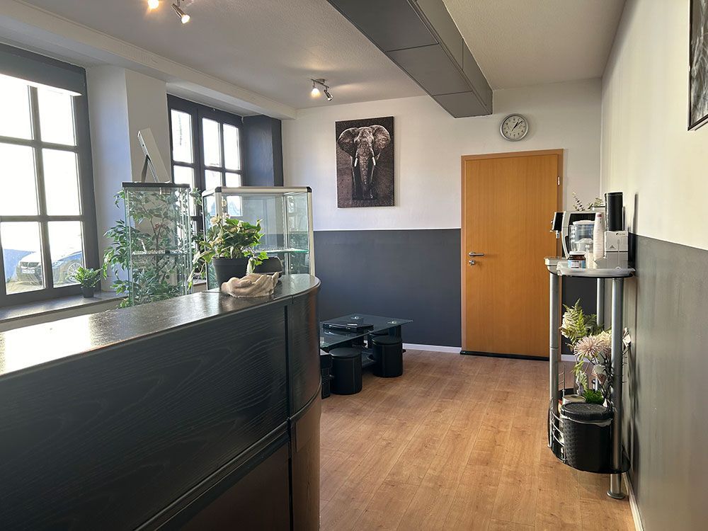 Ein Wartezimmer mit einer Uhr an der Wand und einem Gemälde eines Elefanten.