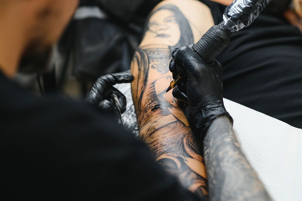 Eine Person lässt sich ein Tattoo auf den Arm machen.