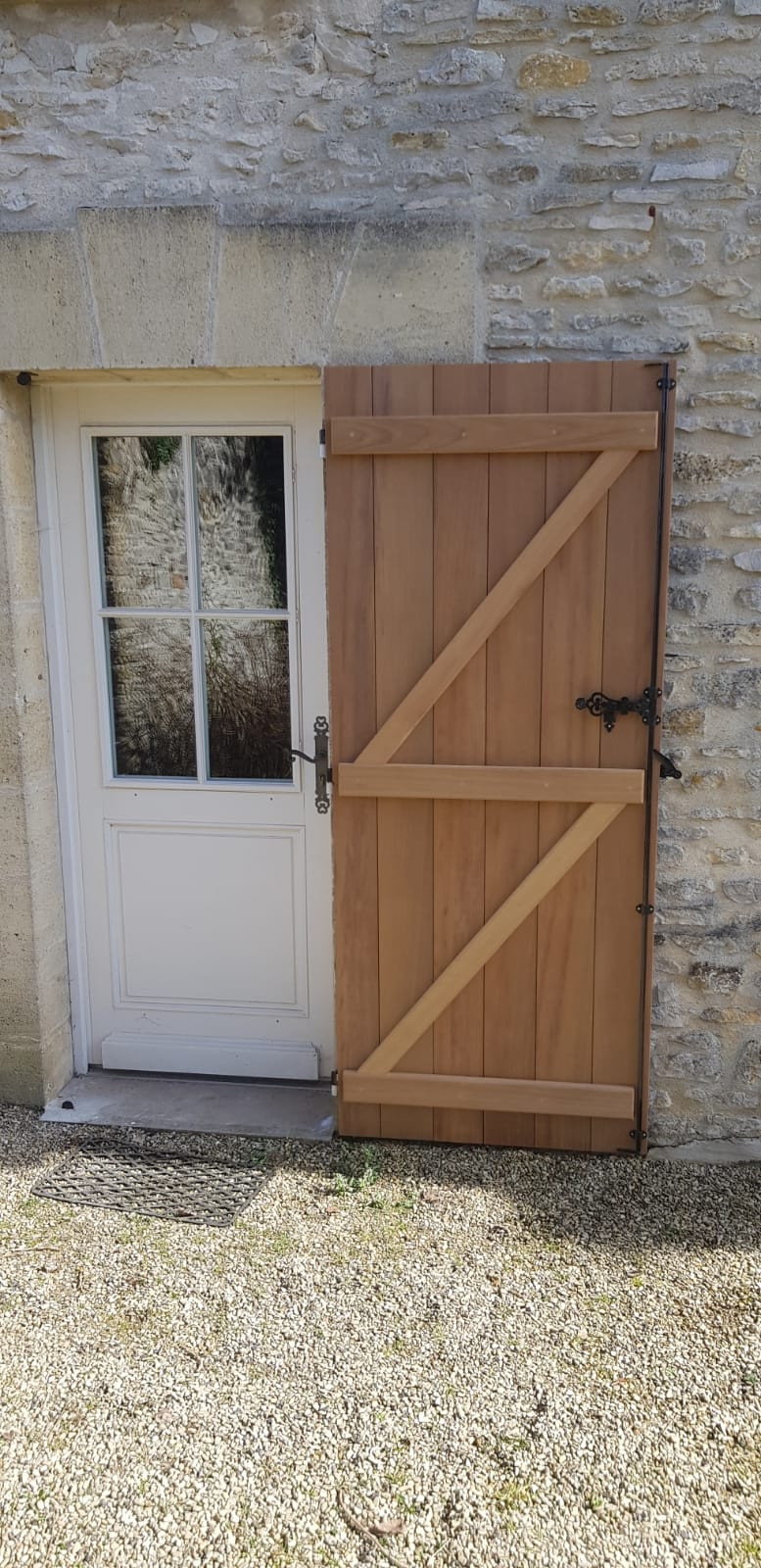 Porte d'entrée blanche et vitrée avec un volet en bois