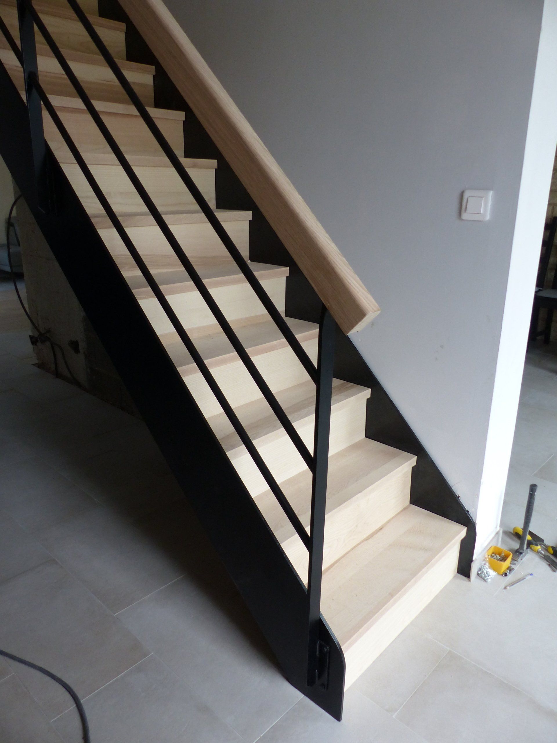 Escaliers avec des marches en bois clair et les rampants noirs