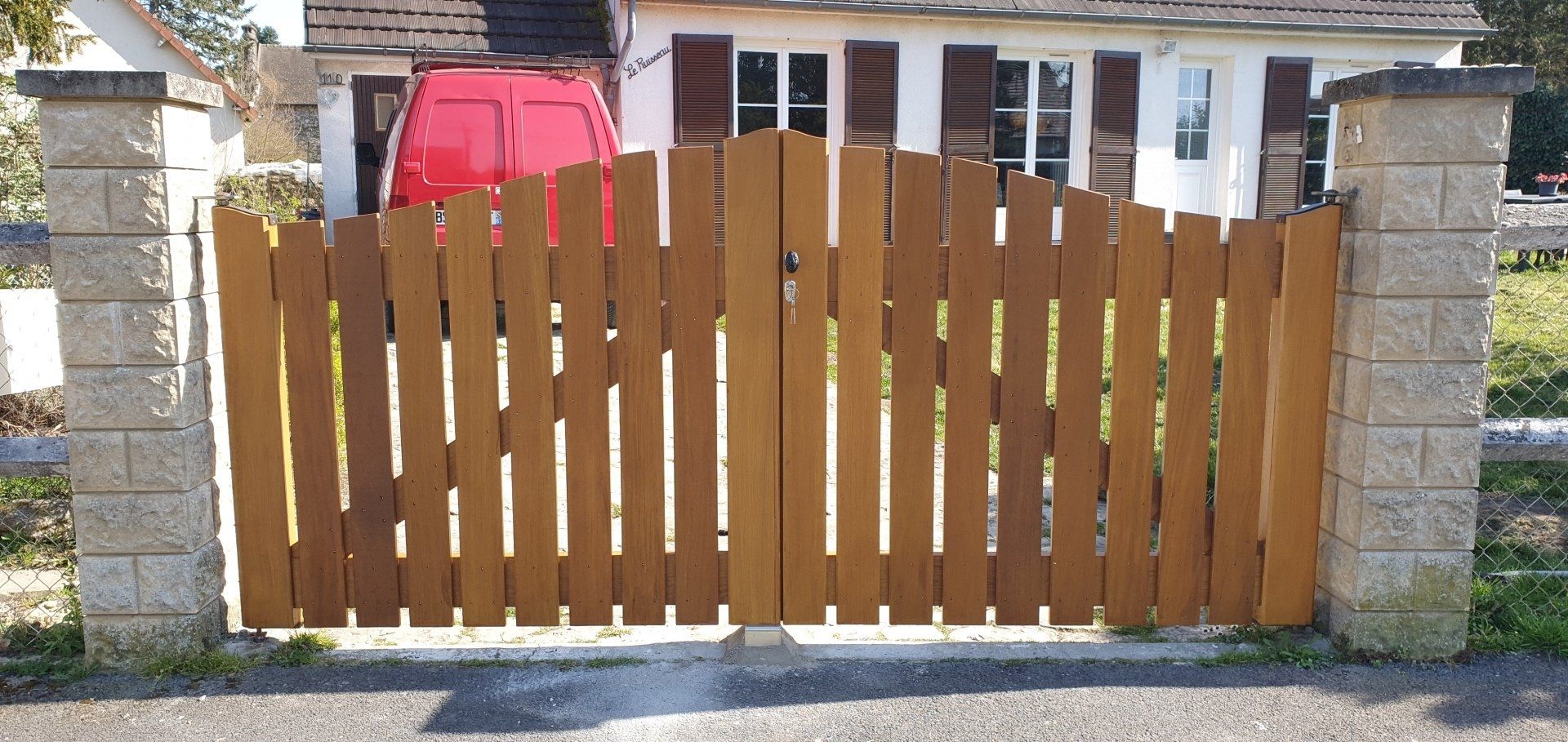 Portail en bois avec une camoniette rouge
