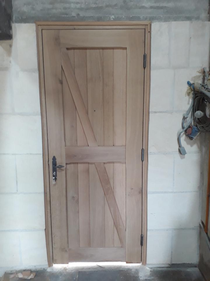 Porte d'entrée en bois clair dans un mur de pierre