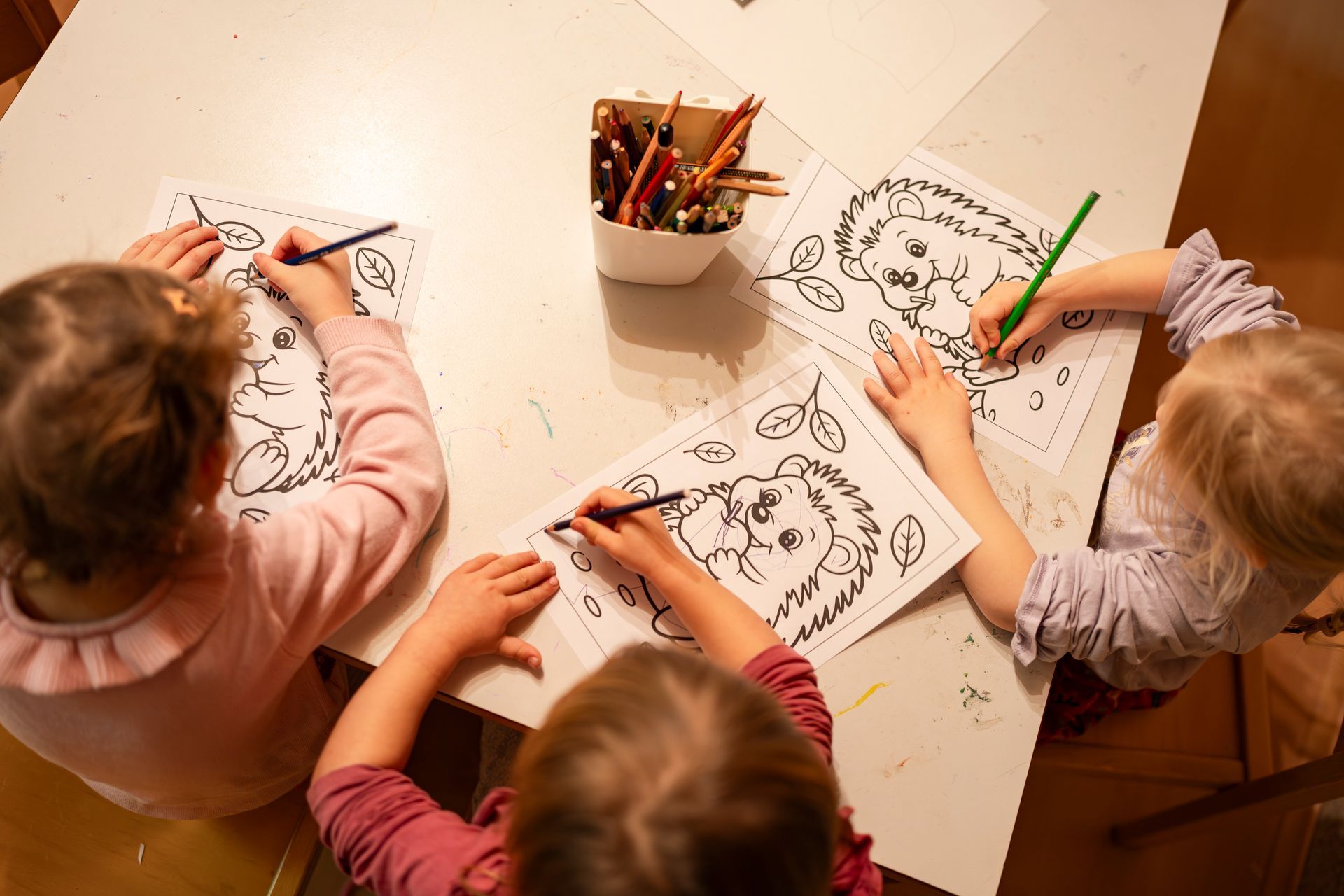 Drei Kinder und eine Person spielen drinnen mit einem Fussball; leuchtend orangefarbener Boden und gelbe Wand.