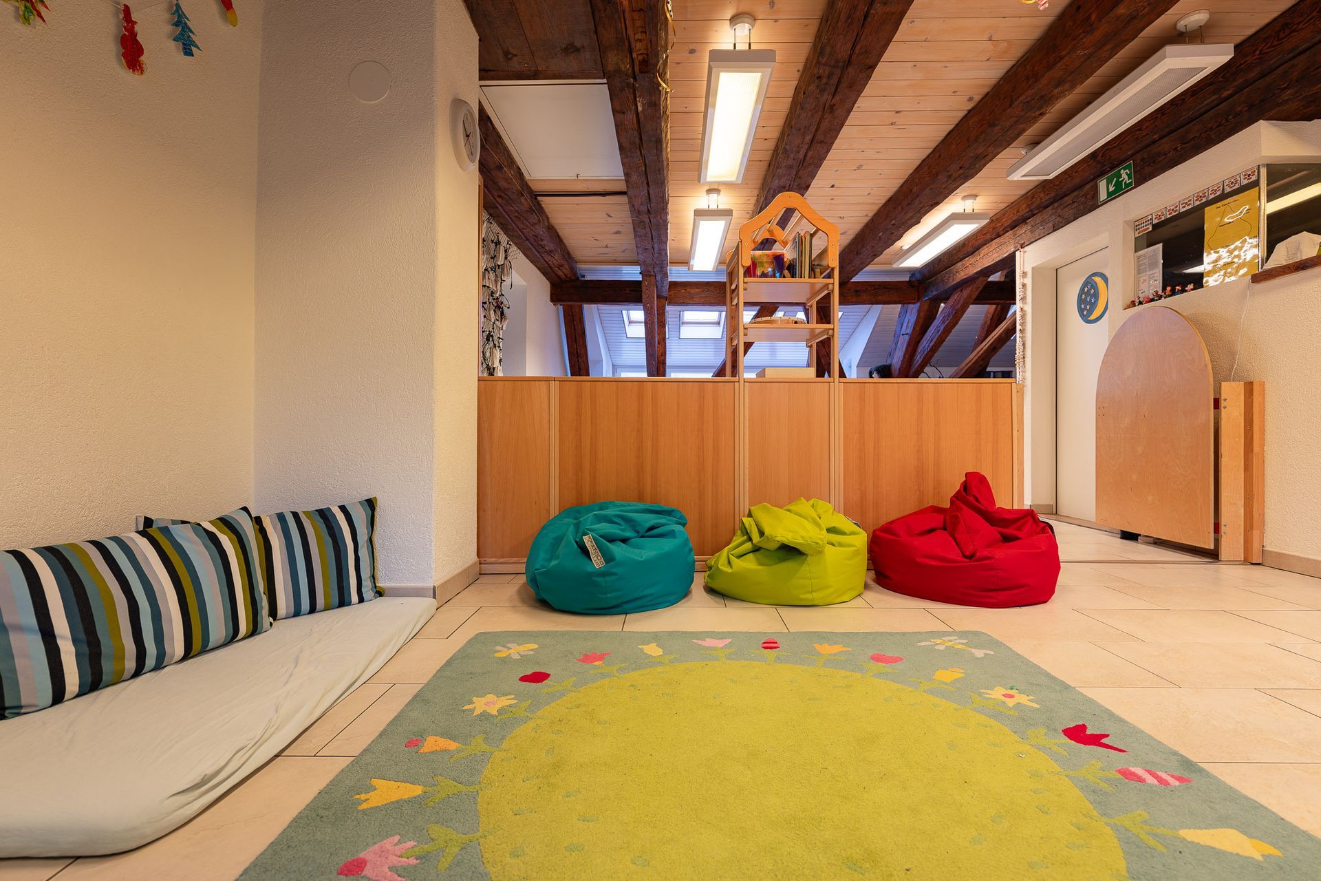 Spielzimmer mit Sitzsäcken, Teppich und gepolsterter Bank.