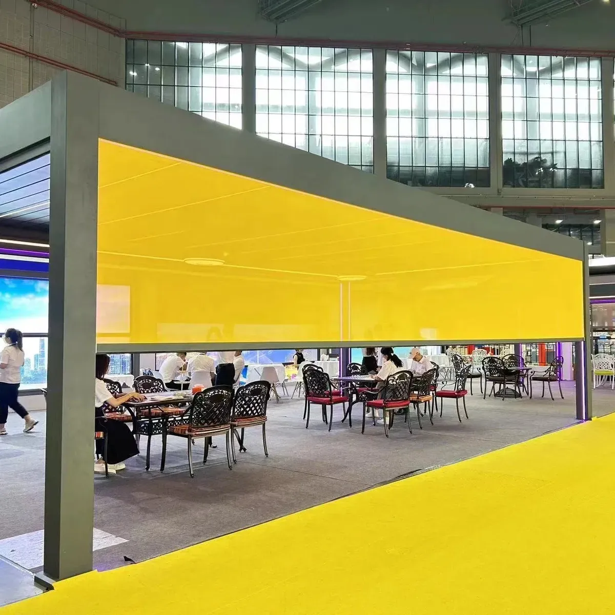 Eine Veranda mit Tischen und Stühlen und einer gelben Wand