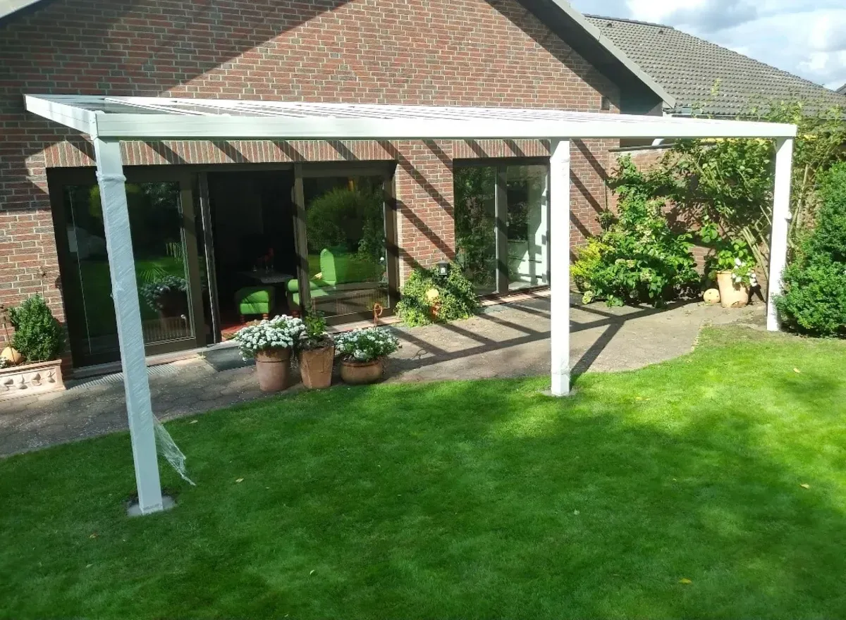 Ein Backsteinhaus mit einer weißen Pergola davor