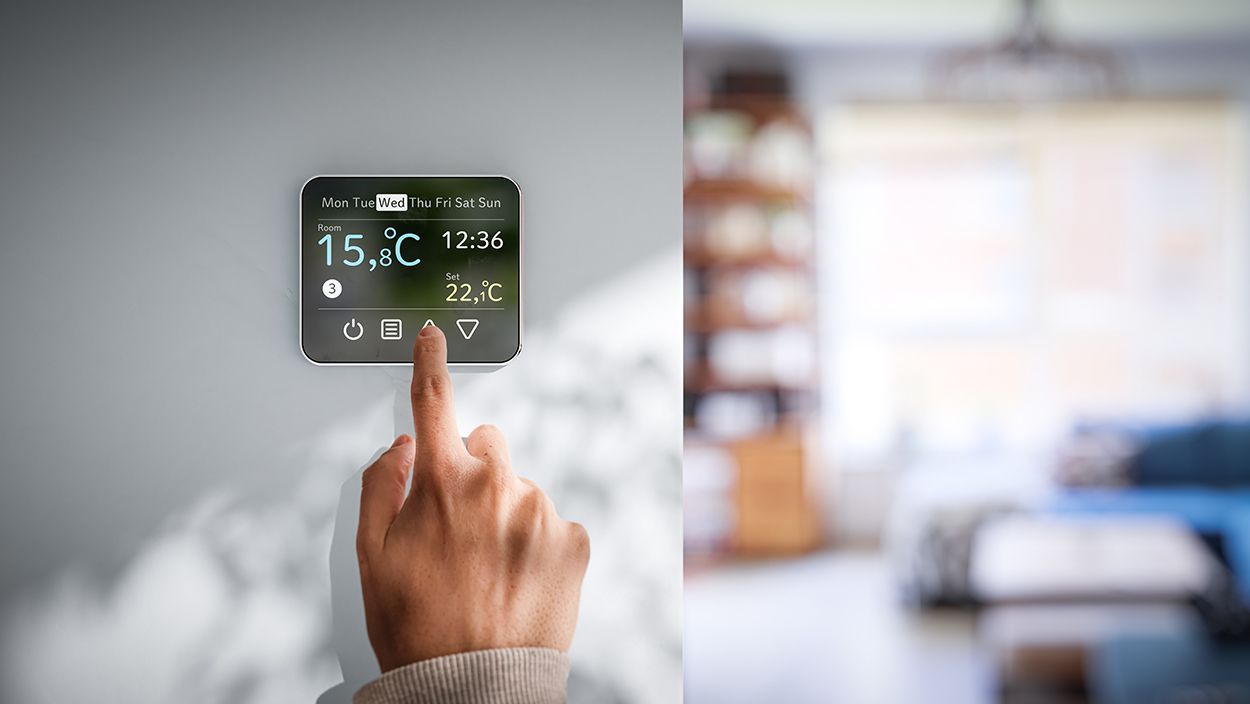 Doigt pointé sur le thermostat d'une maison