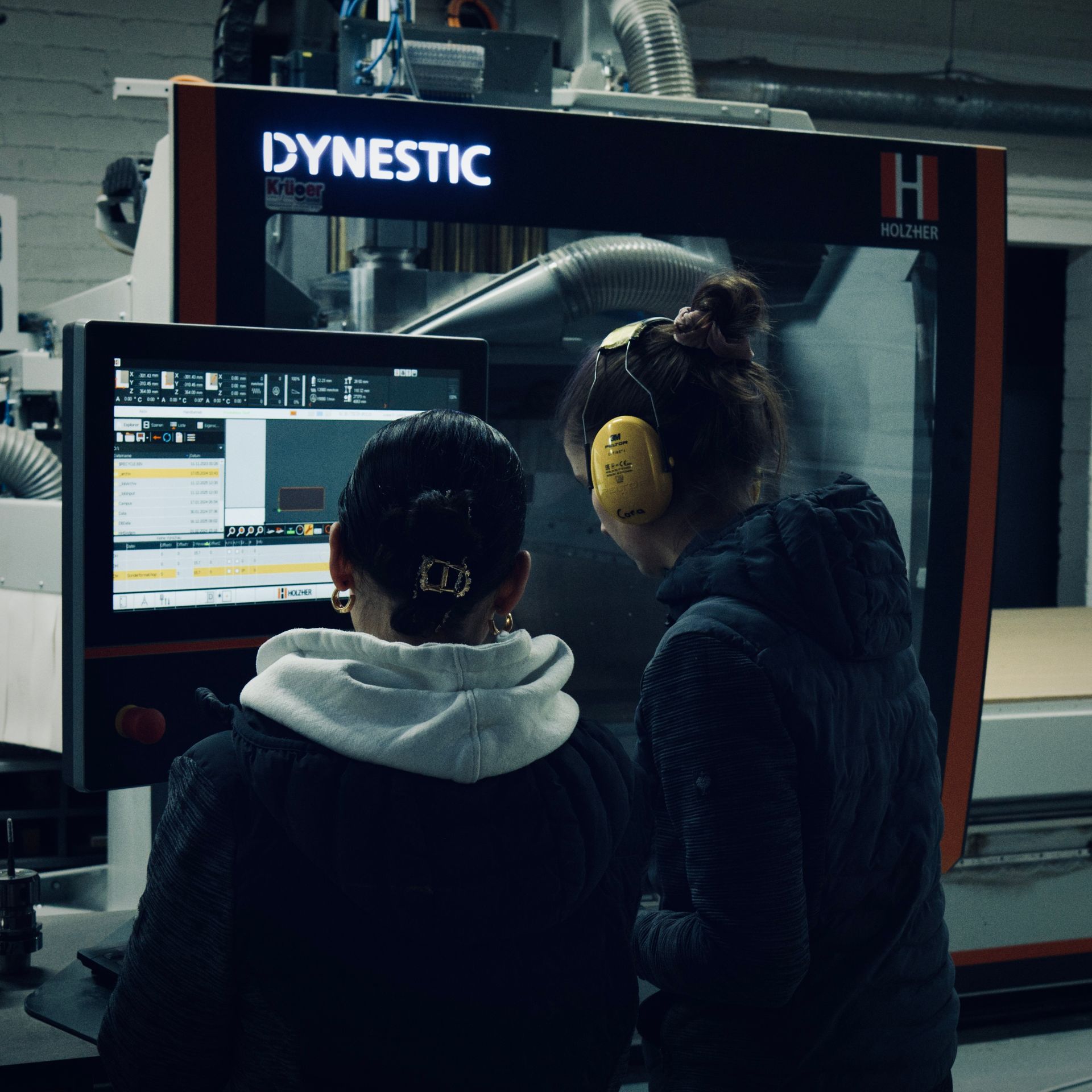 Zwei Personen bedienen eine DYNESTIC CNC-Maschine in einer Werkstatt