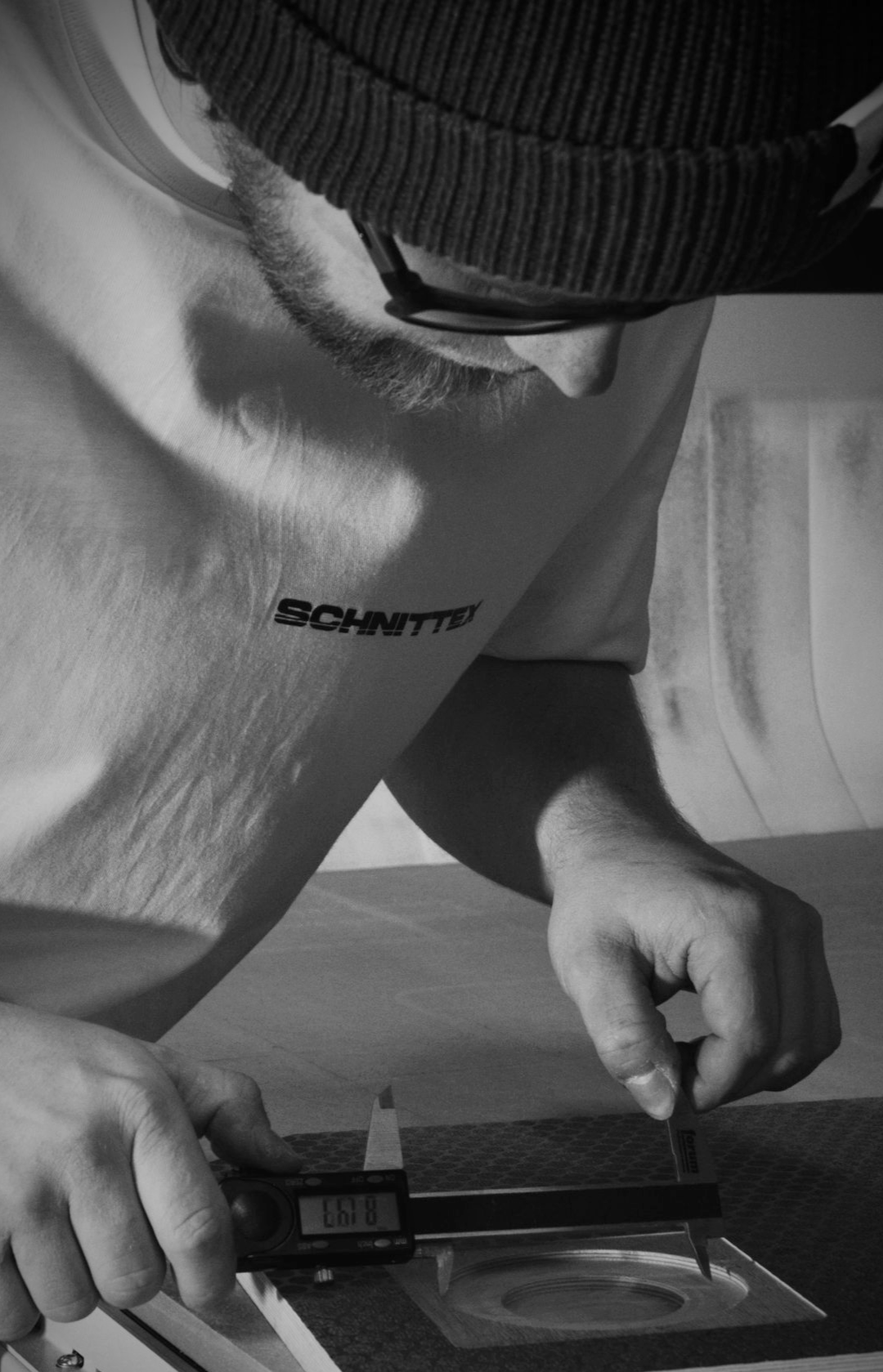 Person mit Hut und Brille, die mit einem Messschieber ein Objekt misst.