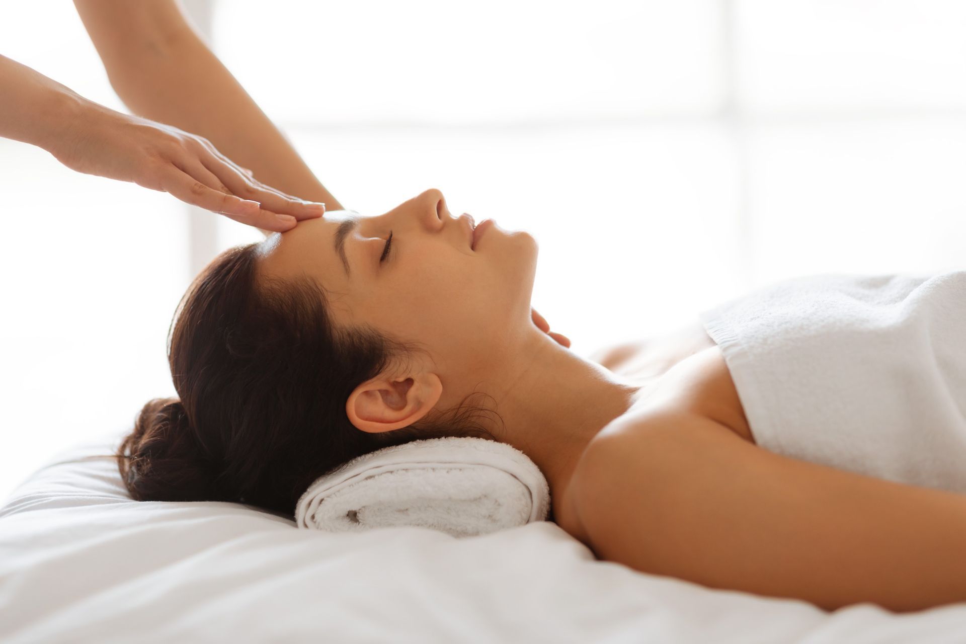 Una mujer está acostada en una cama recibiendo un masaje facial.