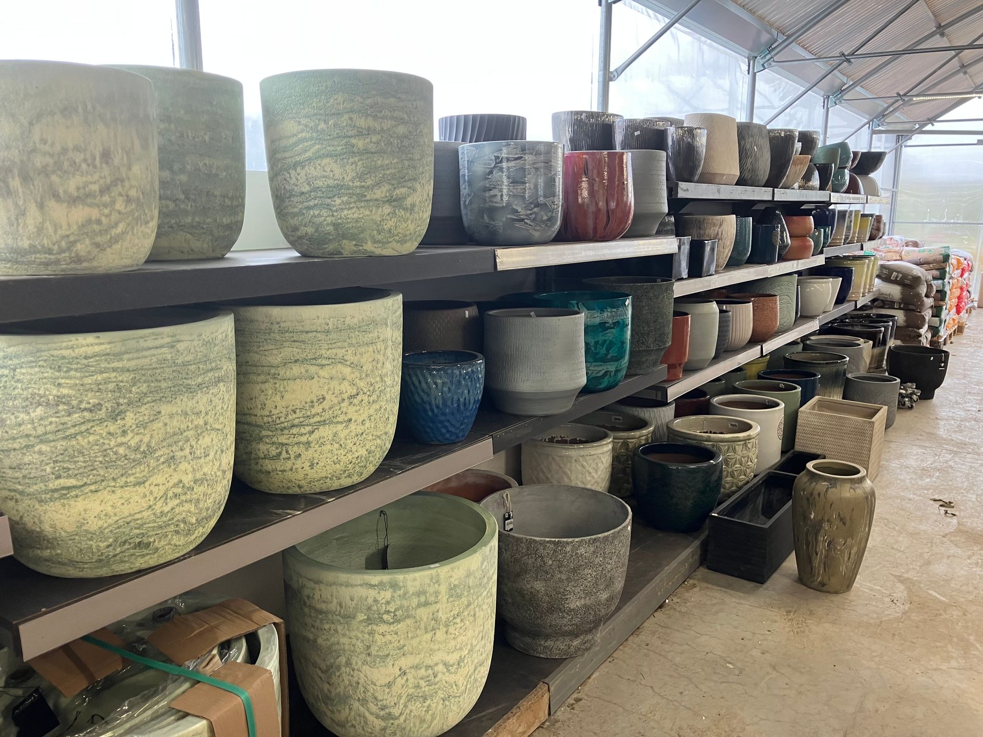 Des étagères dans une chambre d'enfant remplies de pots de fleurs en céramique de tailles, textures et couleurs neutres variées.