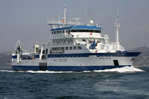 Un gran barco blanco y azul flota sobre un cuerpo de agua.