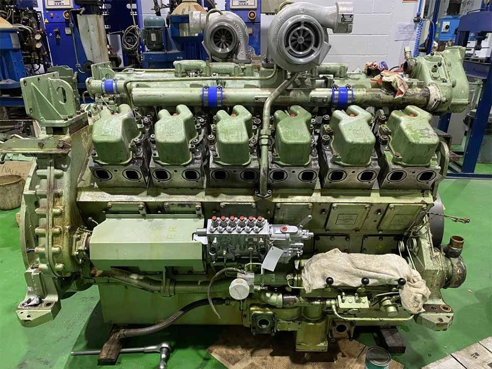 Un gran motor se encuentra sobre un suelo verde en una fábrica.