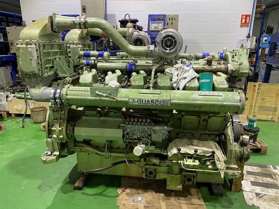 Un gran motor se encuentra sobre un suelo verde en una fábrica.