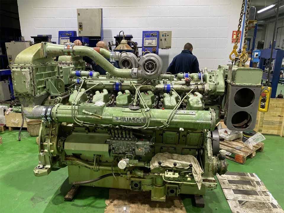 Un gran motor verde está situado sobre un suelo verde en una fábrica.