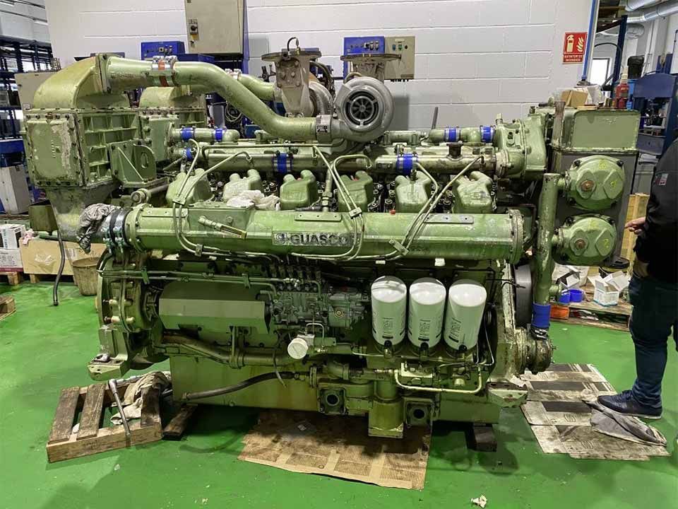 Un gran motor verde está situado sobre un suelo verde en una fábrica.