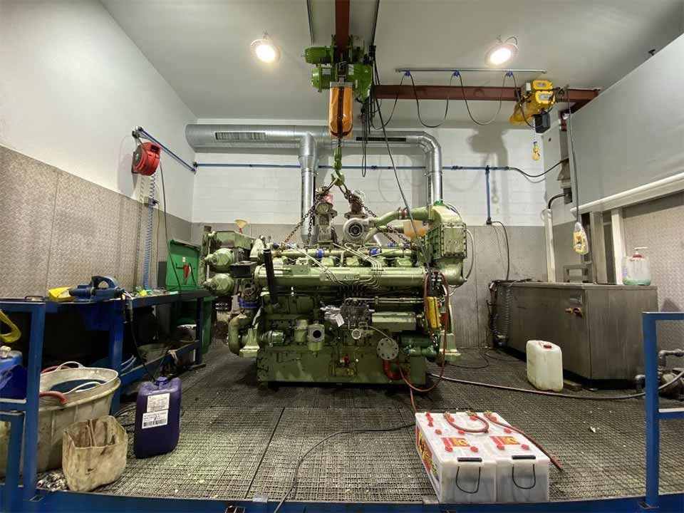 En un garaje se está trabajando en un motor grande.